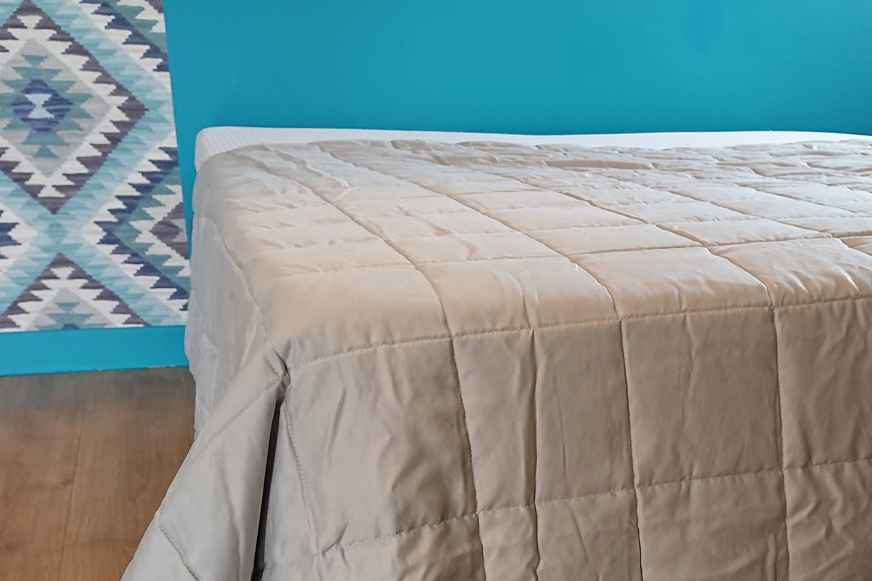 Cobertor pesado cinzento a cobrir uma cama.